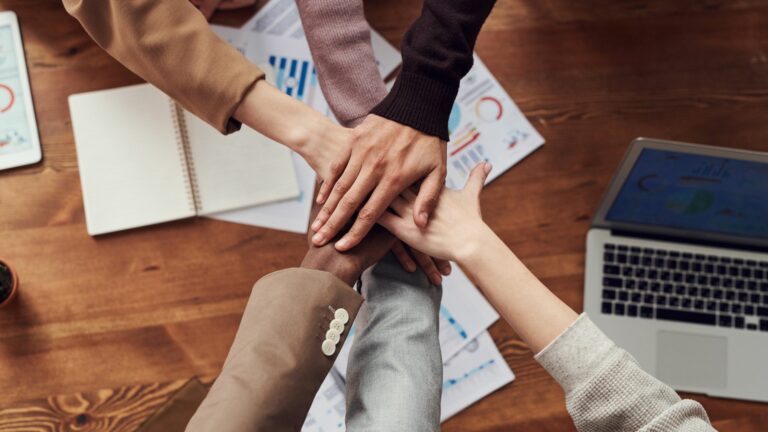 People's hands on top of each others hands, showing teamwork